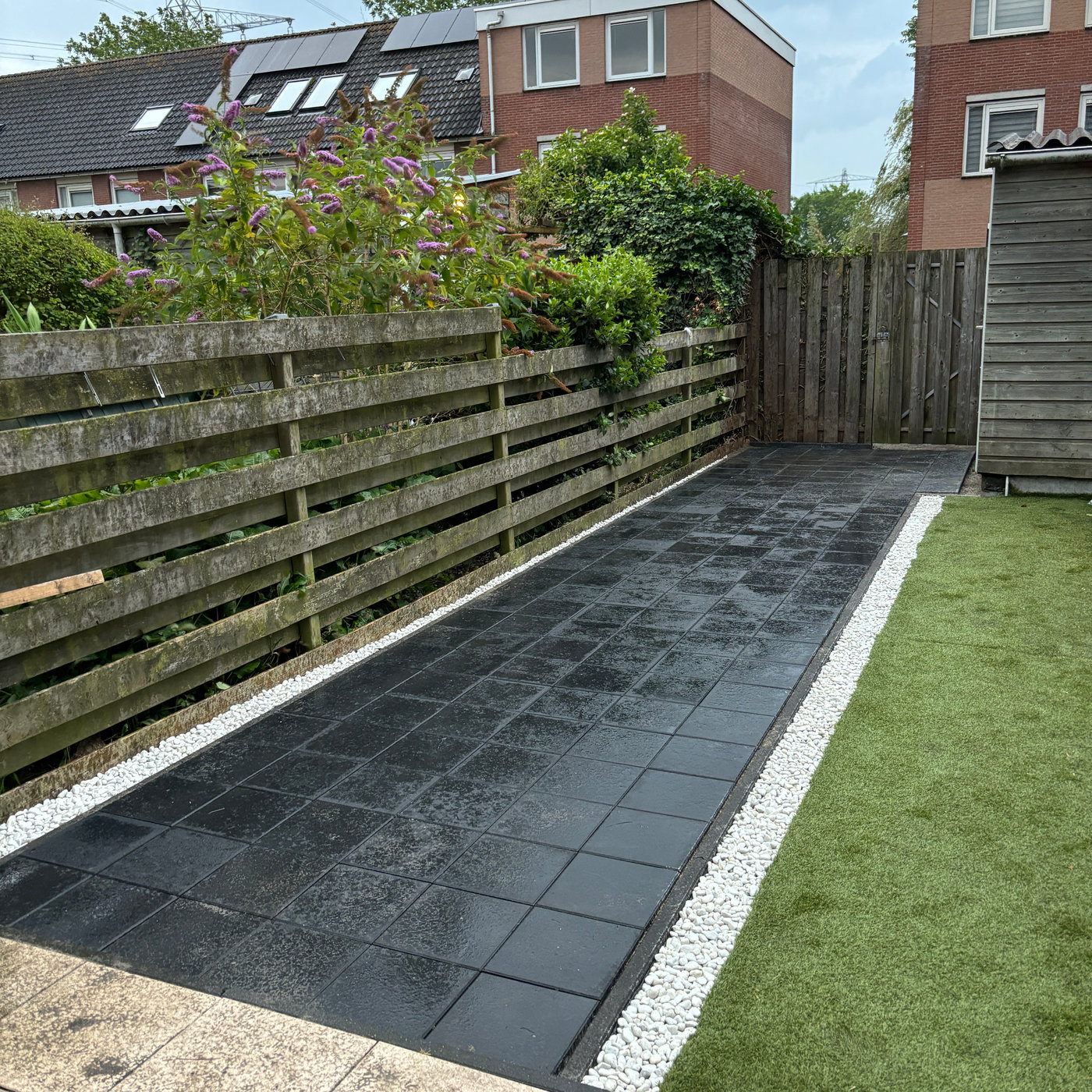 Tuinpad met zwarte tegels en siergrind aangelegd door NT Bouwgroen